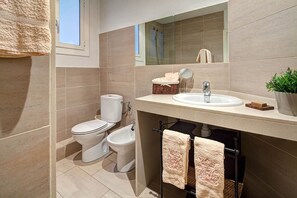 Un bany modern amb vàter, bidet, rentamig i un mirall sobre el rentamig.
