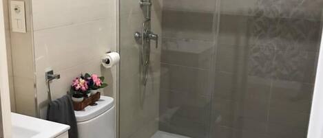 Un baño con inodoro, ducha y lavamanos.