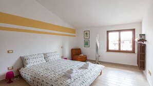 Um quarto com uma cama, uma cadeira, um radiador e uma janela.