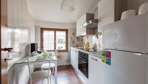 A modern kitchen with white cabinets, a built-in oven, and a refrigerator.