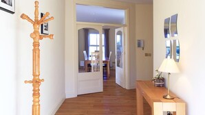 A hallway with wooden flooring, a coat rack, a lamp, and a dining area in the background. - Bun Cill Athat - secluded mountainside location overlooking Kenmare Bay & Area (Kenmare)