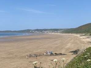 A wide sandy beach with a few people and a tent set up near the water.
