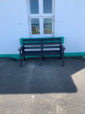 A bench with a white and green painted wall behind it.