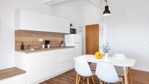 A modern kitchen with white cabinets, a wooden countertop, a white dining table with two chairs, and a pendant light. - Apartment Arausa with Pool IX (Vodice)