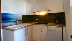 A kitchen with white cabinets, a granite countertop, a coffee maker, and a dishwasher. - APARTMENT PUEBLO AMARRES 2D (L'Escala)