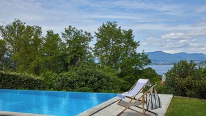 A swimming pool with a lounge chair and a tray with a glass and napkin. - MAJOR LAKE VILLA WITH GARDEN & SWIMMING POOL. AMAZING VIEW ON THE LAKE AND ALPS (Ranco)