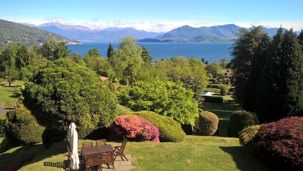A lush garden with a wooden table and chairs, surrounded by various trees and shrubs. - MAJOR LAKE VILLA WITH GARDEN & SWIMMING POOL. AMAZING VIEW ON THE LAKE AND ALPS (Ranco)