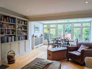 A spacious living room with a fireplace, a dining area, and a large window offering a view of greenery.