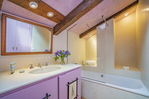 A bathroom with a double sink vanity, a large mirror, a shower area, and a bathtub.