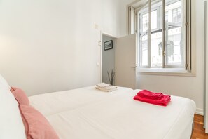 A bedroom with a bed, a window, and a door.