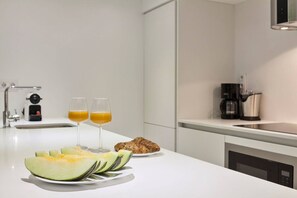 A modern kitchen with a white countertop, a coffee maker, and a microwave.
