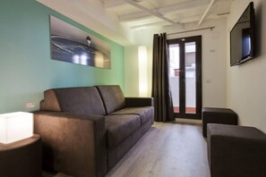 A modern living room with a sofa, a side table, and a flat-screen TV mounted on the wall.