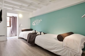 A hotel room with two beds, a teal accent wall, and a fish mural.