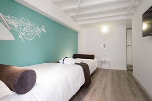 A hotel room with a bed, a bedside table, a wall-mounted TV, and a door leading to another room.