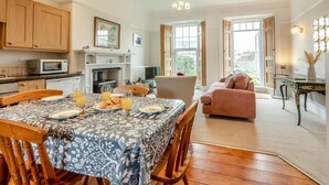 A dining area with a table set for breakfast, a sofa, and a fireplace. - 2 Bed in Mortehoe (oc-mail1) (Mortehoe)