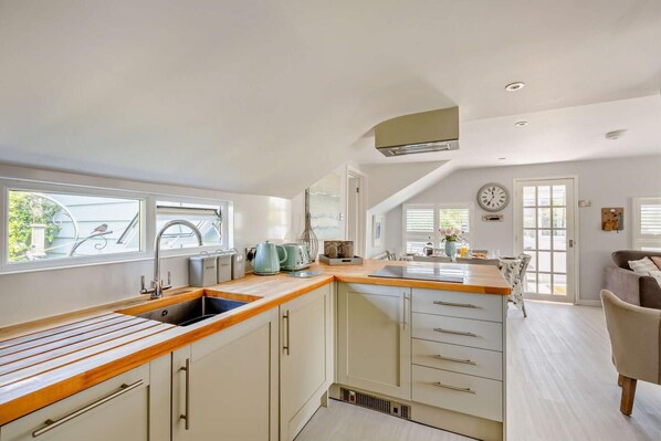 A kitchen with a wooden countertop, a sink, and a dining area with a table and chairs.