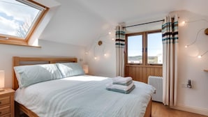 Une chambre avec un lit en bois, un puits de lumière, un radiateur et une fenêtre avec des rideaux.
