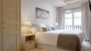 A bedroom with a bed, bedside tables, a nightstand, a window with curtains, and a painting on the wall. - Val de Ruda Luxe 51 by FeelFree Rentals (Baqueira)