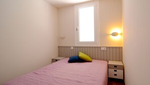 Una camera da letto con un letto, due comodini, una finestra e una lampada fissata al muro.