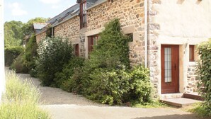Un bâtiment en pierre avec un toit en pente, une porte en bois et un petit porche.