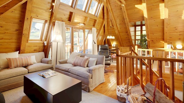 A cozy wooden cabin with a loft bedroom, a living area with sofas and a coffee table, and a dining area with a table and chairs. - Besiberri by FeelFree Rentals (Garós)