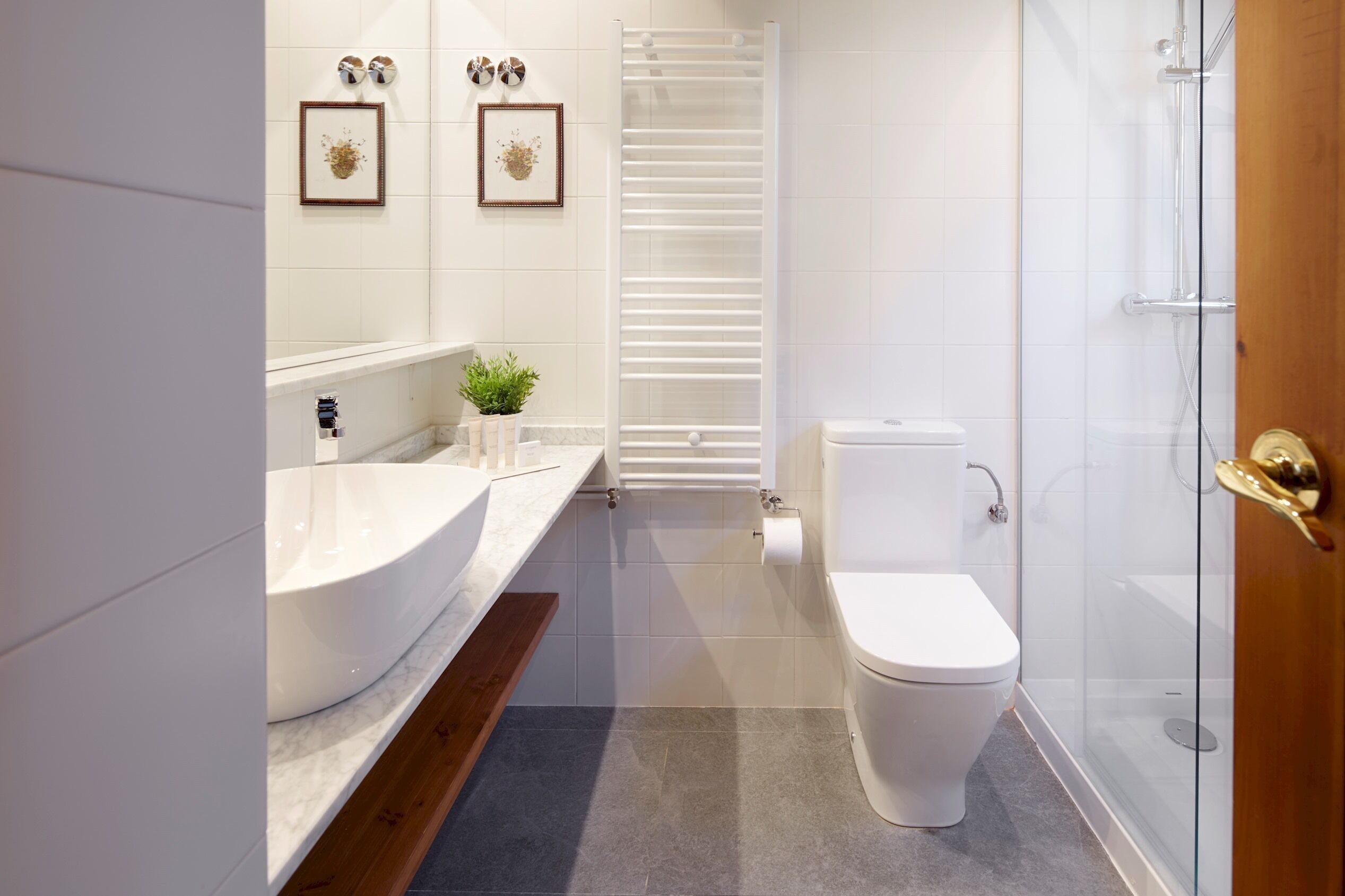 A modern bathroom with a white sink, toilet, and glass shower enclosure.