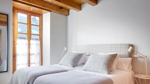 A bedroom with two beds, a window with curtains, a bedside lamp, and a wooden ceiling. - Besiberri by FeelFree Rentals (Garós)