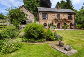 A stone house with a garden, a wooden fence, and a bench. - Mill Cottage, Luxborough (Luxborough)