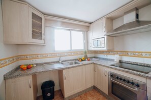 A compact kitchen with a sink, stove, microwave, and cabinets.