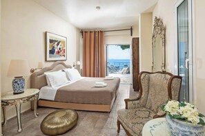 Una habitación de hotel con cama, una silla, una mesa y vista al mar.
