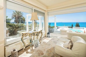 Un balcón amplio con vista al mar, amoblado con sofás blancos y una mesa.