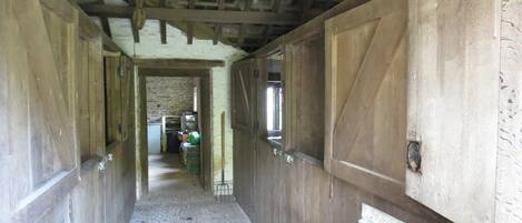 A corridor with wooden walls and a stone floor, leading to a room with a window.