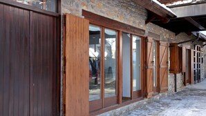 A rustic building with wooden shutters and stone walls, featuring large windows and a snow-covered ground. - Cap 1500 by FeelFree Rentals (Baqueira)