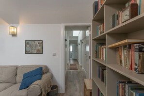 A living room with a sofa, a bookshelf, and a hallway leading to another room.
