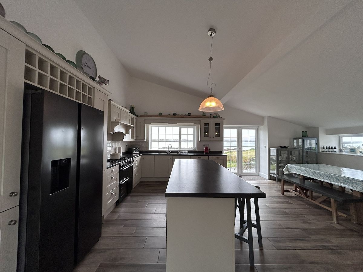 A modern kitchen with a central island, built-in appliances, and a dining area with a bench.