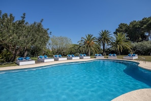 Una piscina con sillas de descanso y cojines azules a lo largo del borde.