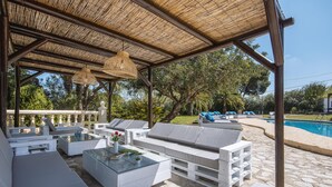 An outdoor lounge area with white furniture, a glass coffee table, and a pool in the background. - Adsubia 12 - Javea, Costa Blanca (Javea)
