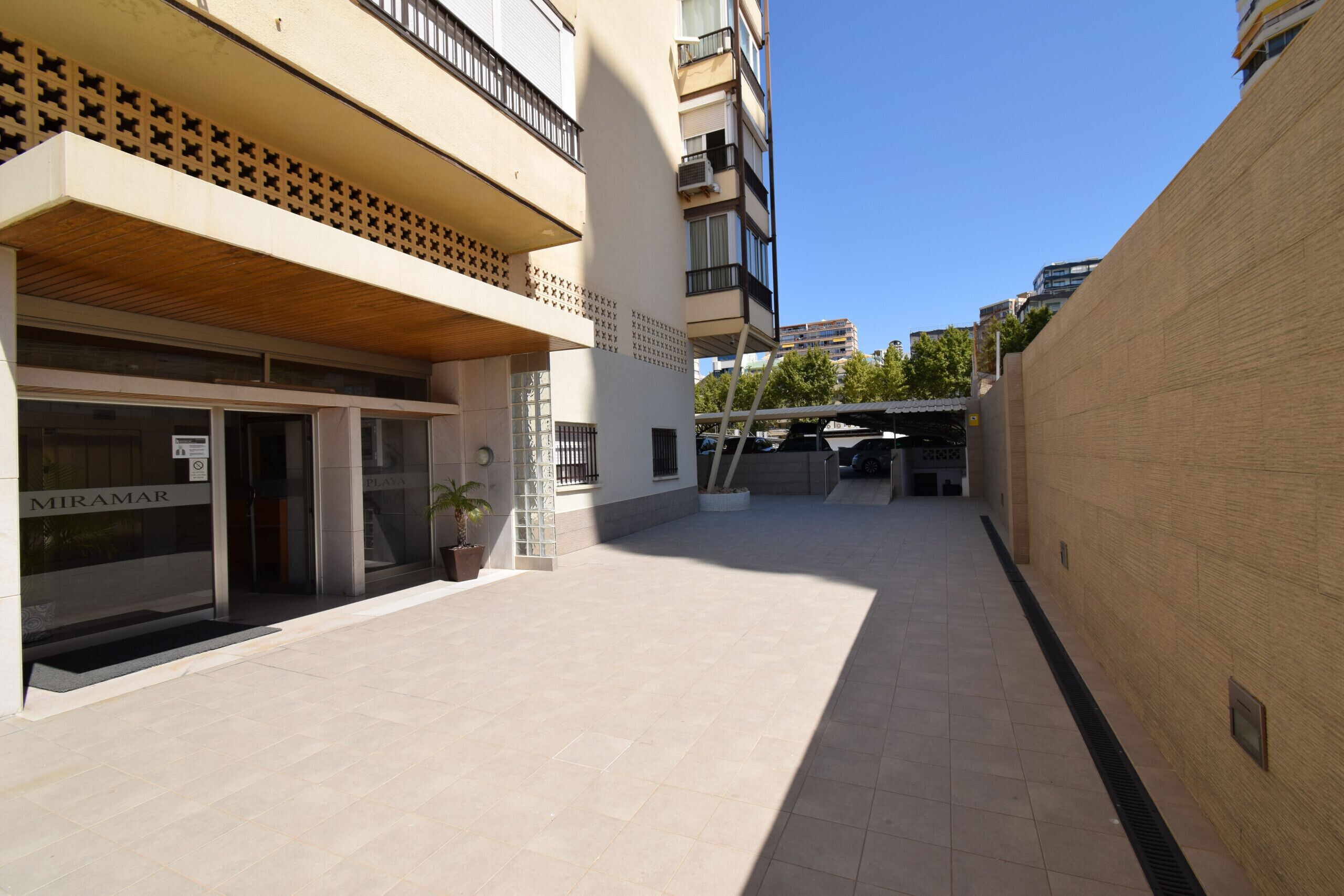 Un edificio moderno con fachada plana, ventanas amplias y una entrada visible con un cartel.
