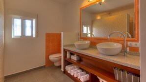 Une salle de bain avec un double lavabo, un grand miroir et des toilettes.