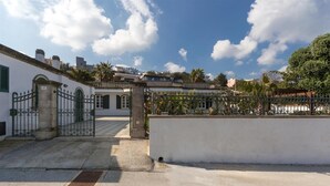 A courtyard with a gated entrance, a white building with green shutters, and a clear blue sky. - La Ripostiera by BarbarHouse (Castro)