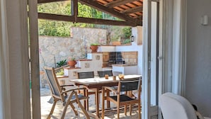 A patio area with a stone wall, wooden furniture, and a brick fireplace.