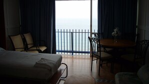 A hotel room with a bed, two chairs, a small table, and a view of the sea through a balcony. - LAS PALMERAS (STUDIO) BENIDORM (Benidorm)