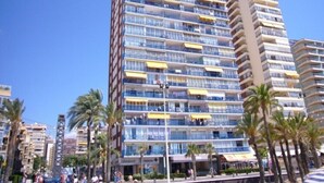 A high-rise hotel with multiple balconies, palm trees, and a clear blue sky. - LAS PALMERAS (STUDIO) BENIDORM (Benidorm)