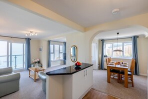 A modern hotel room with a balcony, a dining area, and a living space.