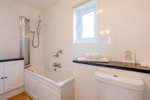 Une salle de bain équipée d’une douche, de toilettes et d’un lavabo, avec une pancarte indiquant qu’il ne faut pas jeter les serviettes hygiéniques dans les toilettes.