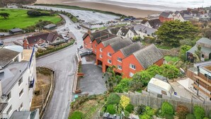 Eine Küstenstadt mit Strand, Wohnhäusern und einer Straße, die zum Meer führt.
