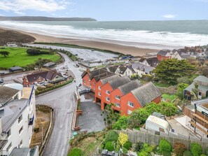 A coastal town with a beach, residential buildings, and a road leading to the sea.