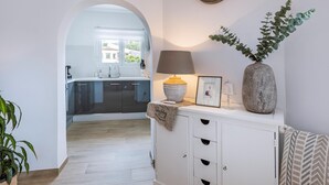 Eine moderne Küche mit Fenster, einer Uhr, einer Vase mit Grünpflanzen und einer Lampe auf einem Schrank.