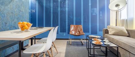 A modern room with a dining table, chairs, a sofa, a coffee table, and a wall with vertical blue panels.