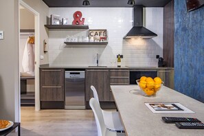 A modern kitchen with a dishwasher, a coffee machine, and a bowl of oranges on the counter.
